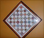 This chessboard of amish quilt designs is from a Better Homes and Gardens Kit purchased in the early 90's.  Stitched by Liz Boily.  It has been used as a chessboard but now hangs in our family room ov