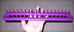 This is the peg-knitting loom, naked.

You can see the grooves on each peg that make it easy to pick up the loops.
