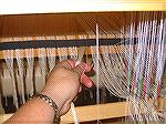 This shows the velcro-lined stick hanging behind the castle with the warp threads from the sectional beam caught in the velcro. This makes it easy to pick the next thread from the current section, and