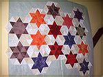 This is an image of partially constructed pyramid star blocks that I'm working on at the moment. The star colours vary from subdued to brighter but are mainly more muted and the background fabrics are
