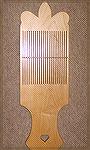 This paddle loom (made by Jonathan Seidel) is a rigid heddle that you hold between your knees while weaving.  This one is made of maple and has a special shaping on the top.

It's a wonderful way to