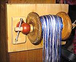 This is a cobbled-together thing to help control long warps for narrow weavings.

Its wooden parts are: an old spool, some scrap pine board, a dowel for the axle, two small curtain-rod supports to h