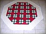 This a 53 inch Octagon.  Primarily 9 patch blocks. It is quilted and waiting for its binding.  Before I bind it I need to make a slit from one edge to the middle so it will go around the tree. Then I 
